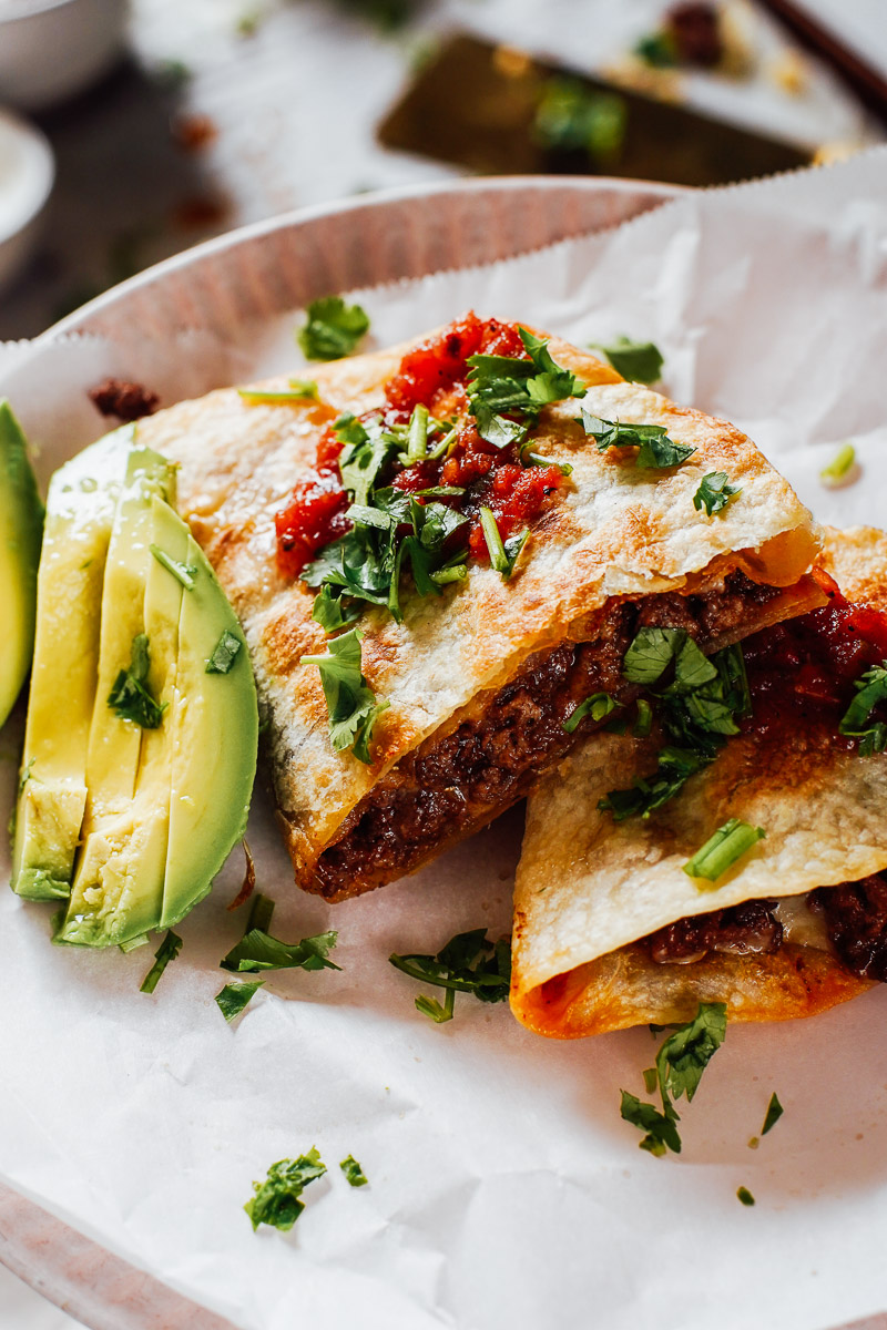 Cooked quesadillas topped with salsa, avocado, and cilantro.