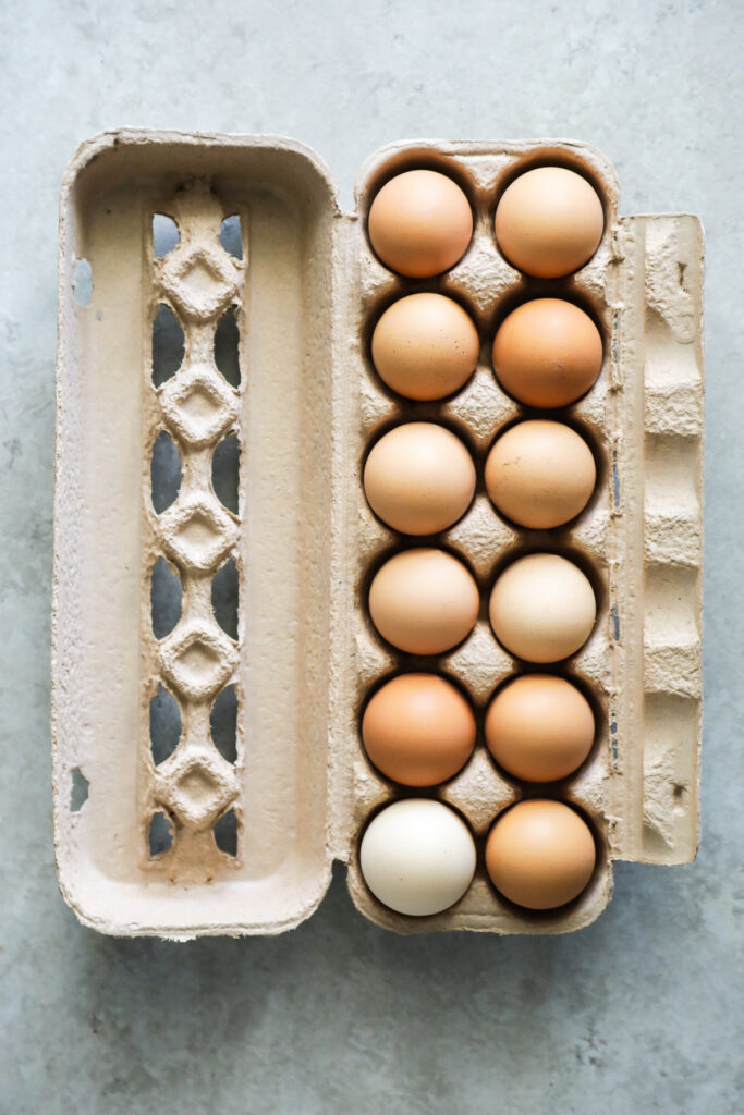 A dozen brown eggs in a brown egg carton.