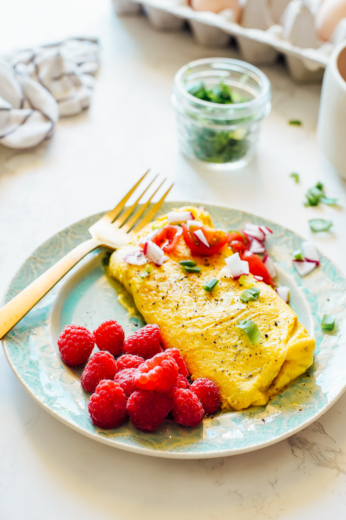 Cheese Omelette on a Blue Plate with raspberries on the side.