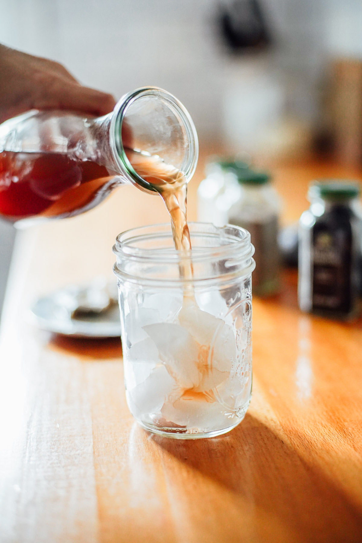 Pouring cold chai concentrate into a glass with ice.