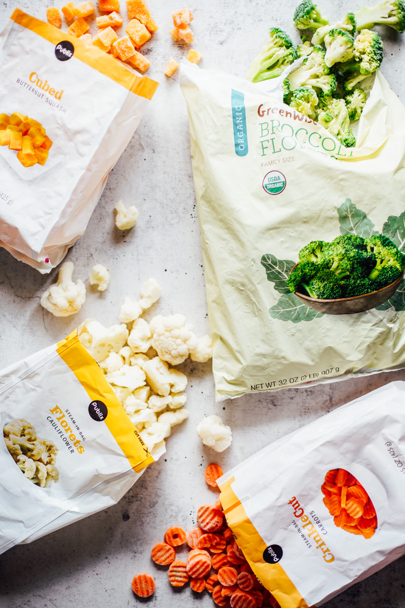 Frozen veggies in bags on a countertop (broccoli, carrots, cauliflower, butternut squash).