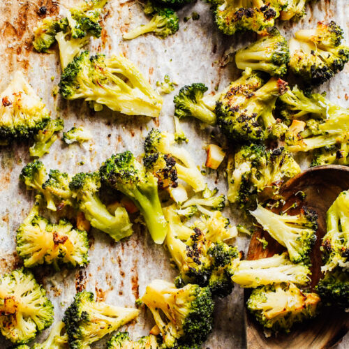 Roasted broccoli on a sheet pan on a kitchen counter.