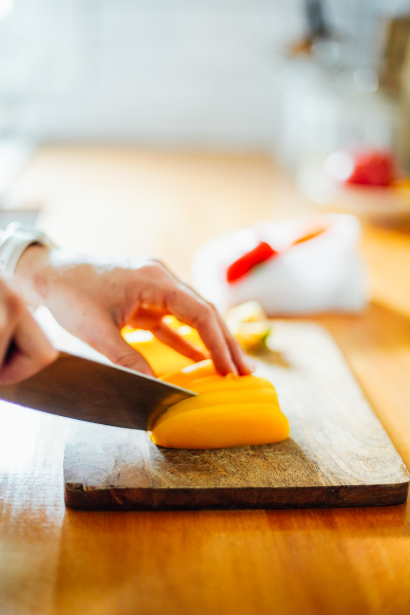 Slicing a yellow bell pepper with a knife into sticks.