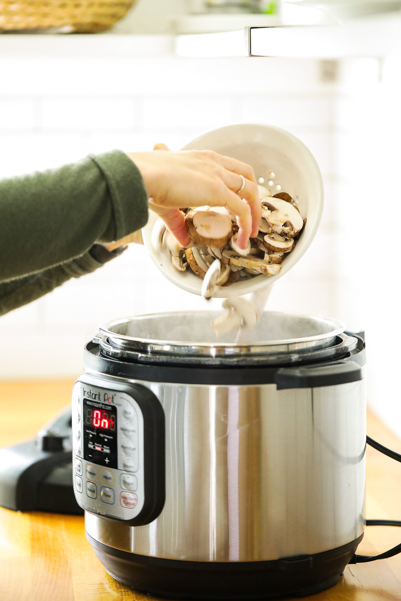 Adding mushrooms to the Instant Pot.