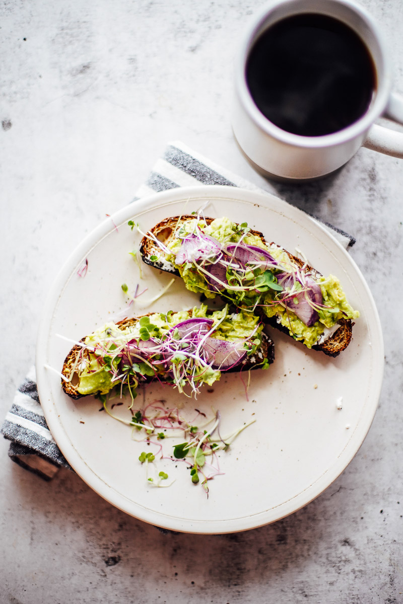 Avocado toast topped with radish slices and sprouts.