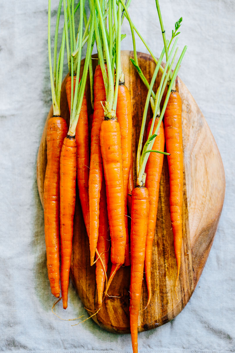 Medium whole carrots on a cutting board.
