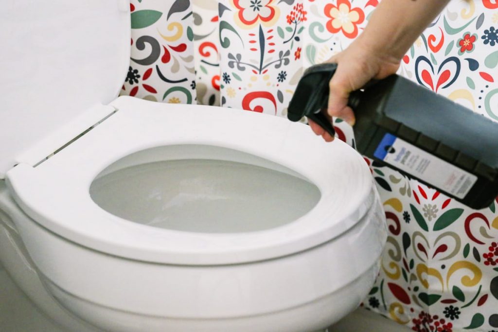 Spraying hydrogen peroxide in the toilet bowl to disinfect. 